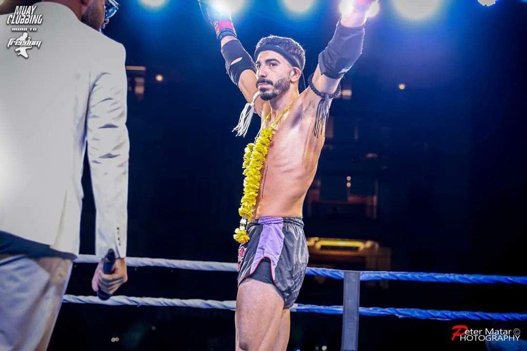 Hussein Ghaddar with both arms raised in the winner's garland after a bout